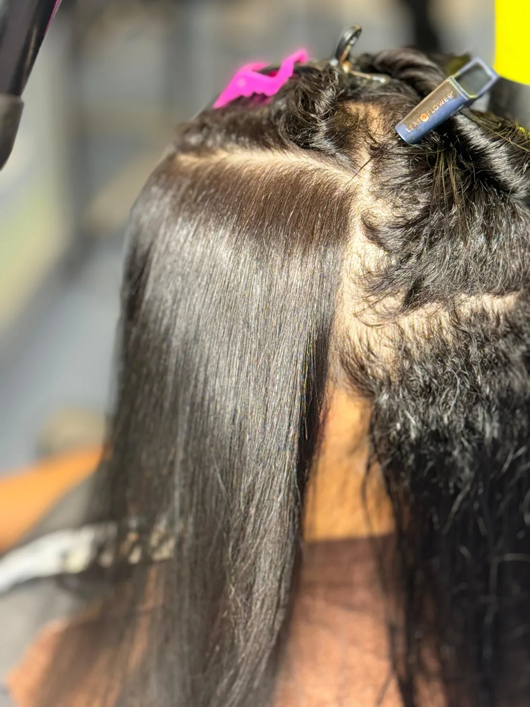 Halfway through an anti-frizz smoothing treatment: smoothed hair on one side next to natural frizzy hair on the other, at Beyond Salon